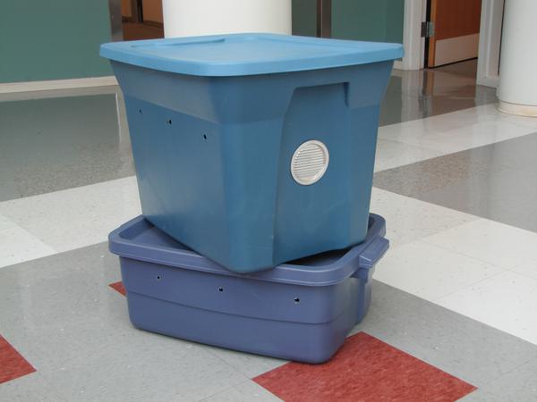 Figure 1. Plastic storage bins in a dark color with tight-fittin